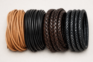 Different types of leather cords including natural leather cord, black dyed leather cord, braided leather cord, and stingray leather cord arranged side by side on a neutral background
