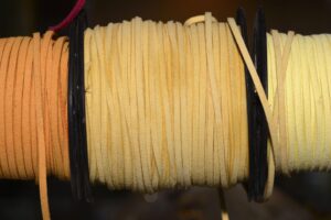 Flat leather cords on spools in natural beige shades