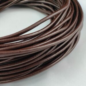 Coiled brown round leather cord on a white background.