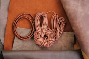 Braided and flat leather cords placed on natural leather sheets.