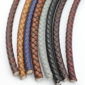 Colorful braided leather cords in multiple shades including brown, blue, grey, black, and red displayed for jewellery making and craft use.