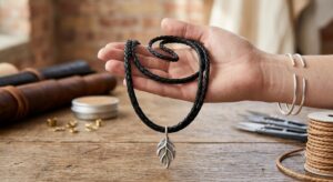 Black woven necklace with leaf pendant drape test on wooden table